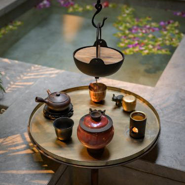 Elegant tea set on a round table by a water feature illustrating multi-sensory interior design tips