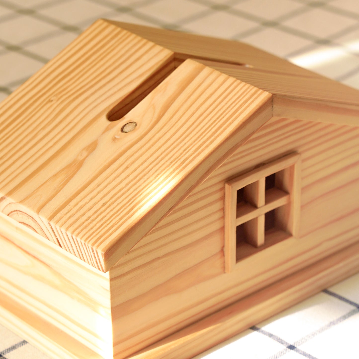 A Good Life cabin style tissue holder made of natural wood with a slanted roof and window design