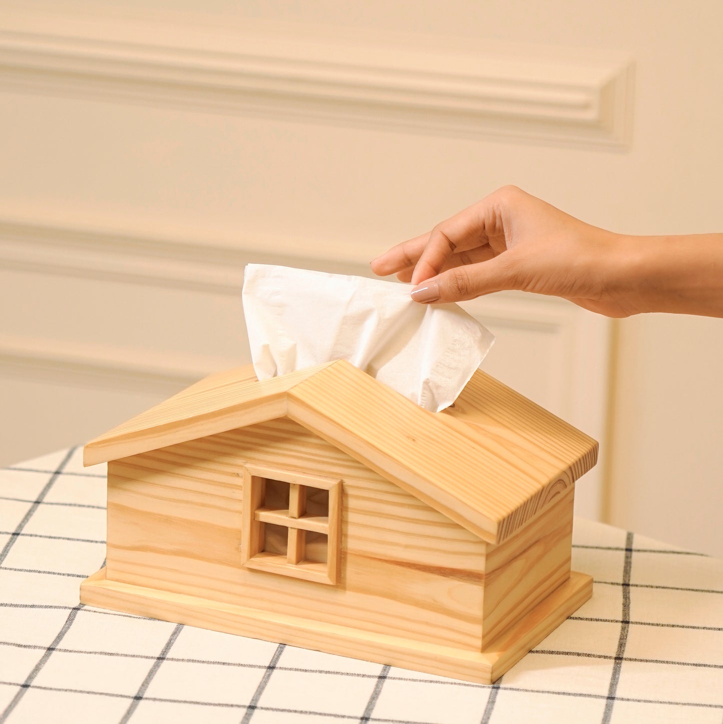 Cabin style tissue holder made of natural wood with a window design on a checkered table