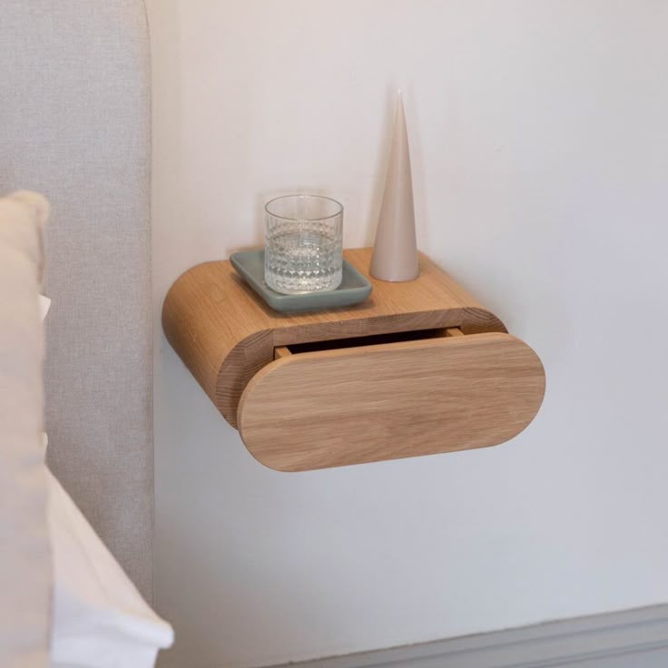 A Good Life minimalist floating bedside table in light wood with a glass of water and a decorative vase