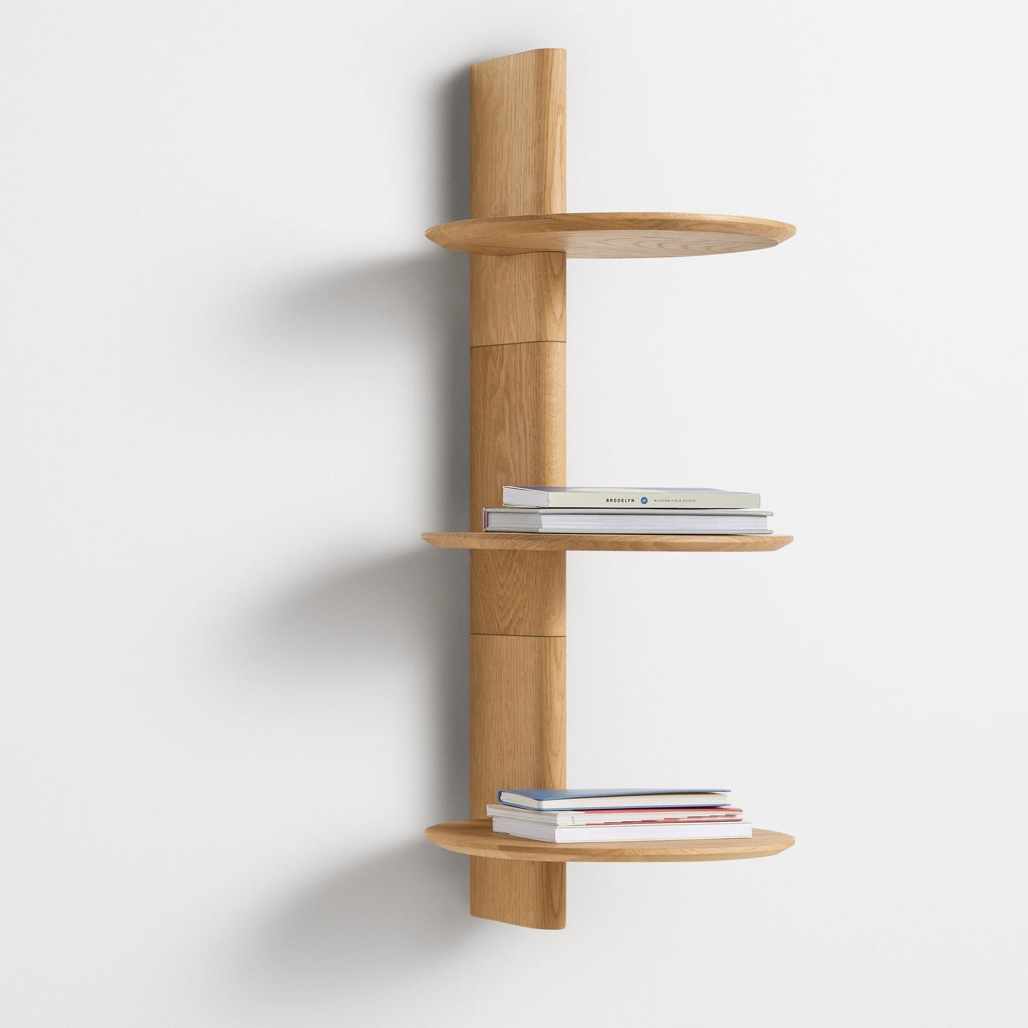 A Good Life pine wood floating shelf with three round tiers mounted on a white wall holding books