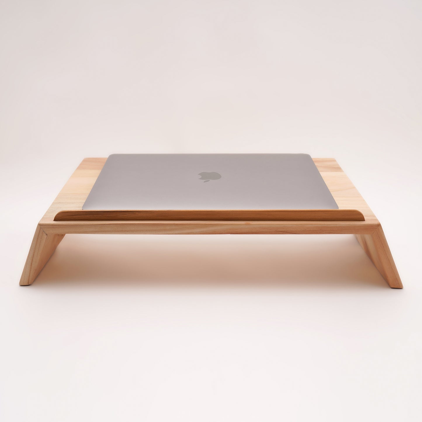 A Good Life pinewood ergonomic work desk laptop stand with a sleek wooden design holding a closed silver laptop
