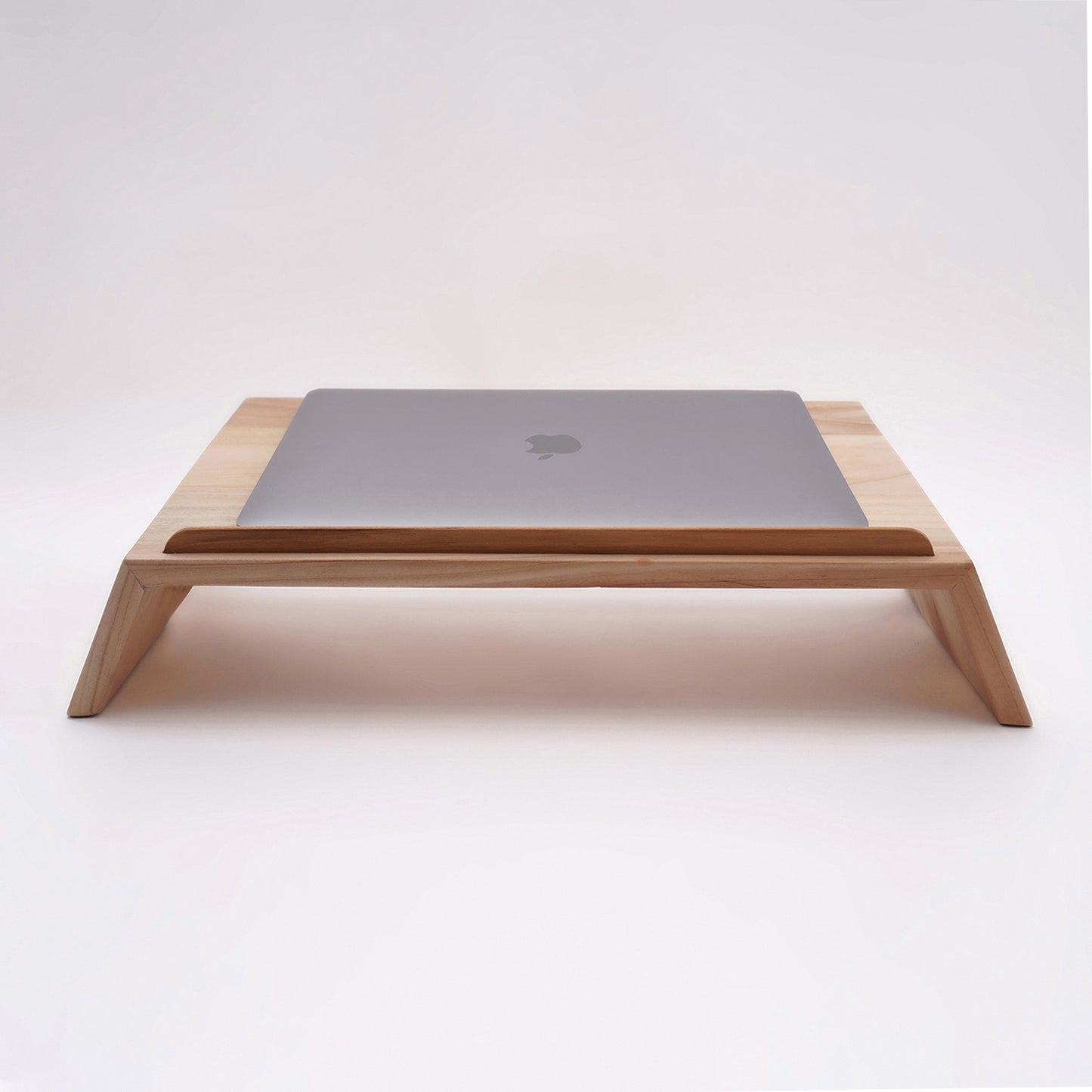 A Good Life pinewood ergonomic work desk laptop stand with a sleek wooden design holding a closed silver laptop