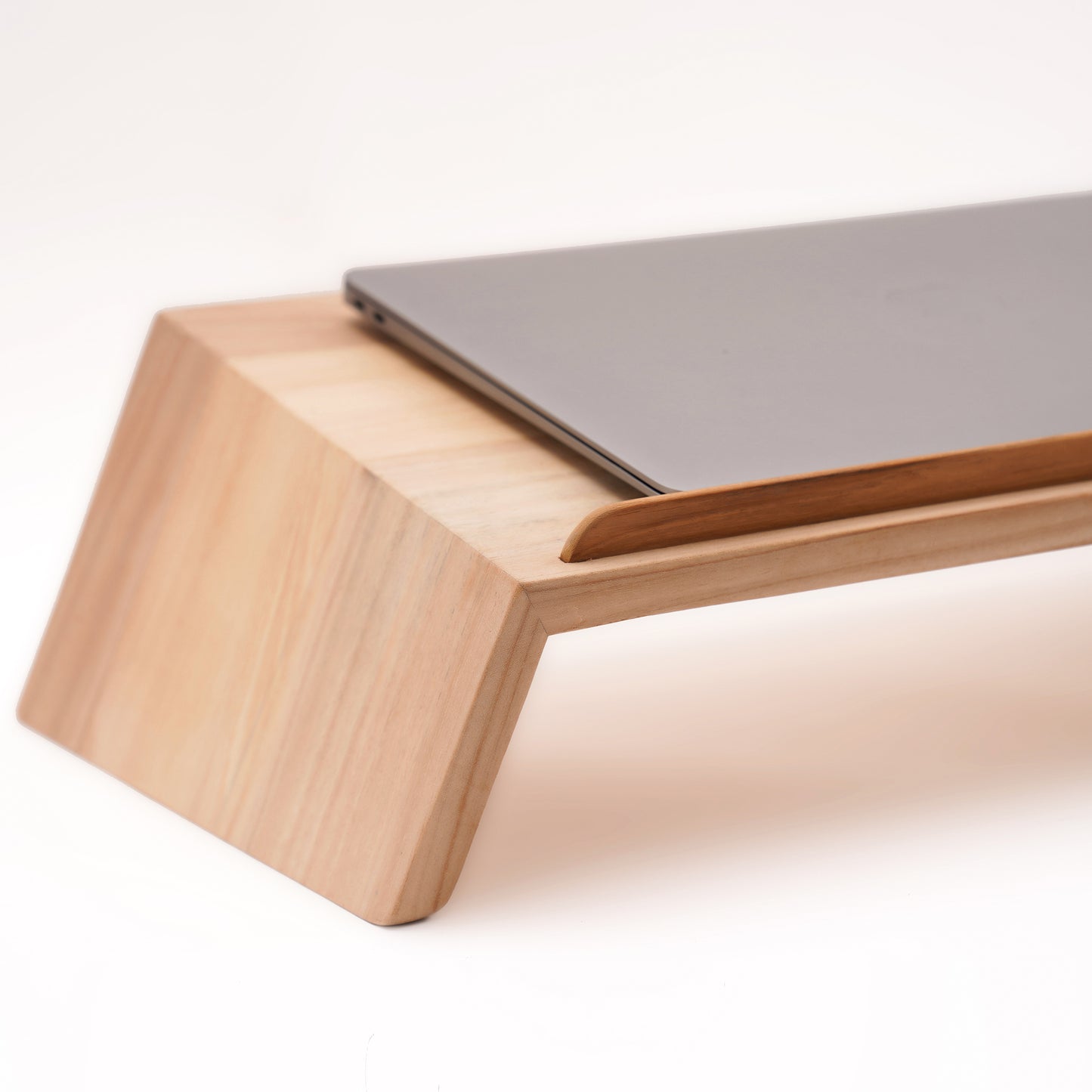 A Good Life laptop stand made from pinewood ergonomic work desk with a sleek, angled design holding a closed laptop