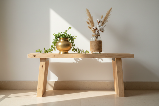 Upcycled home décor vignette with reclaimed light pinewood bench, brass lota planter and jute-wrapped glass jar in a minimalist Indian interior