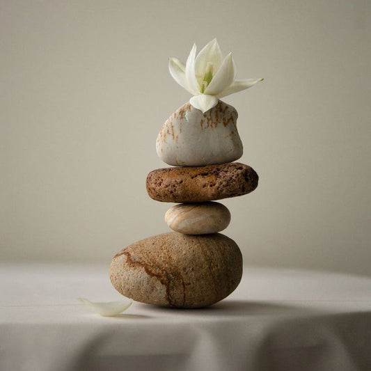 Stacked natural stones with a white flower on top representing balancing aesthetics with functionality in home decor