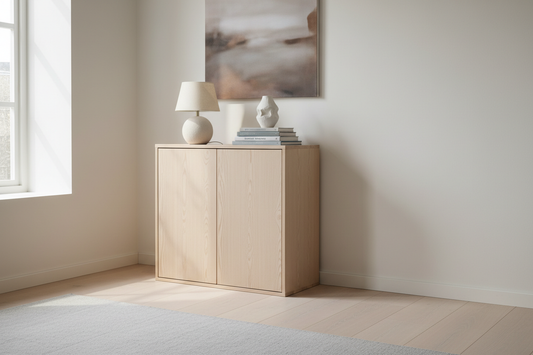 Slim light pinewood storage cabinet with clean lines in a calm minimal living room styled with a lamp, ceramic piece and books