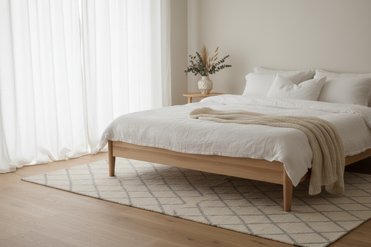 Light pinewood solid wood bed frame and bedside table in a calm minimal Nordic bedroom with white linen and soft natural daylight