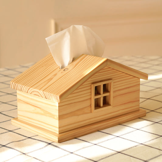 A Good Life cabin style tissue holder made of natural wood shaped like a small house on a checkered tablecloth