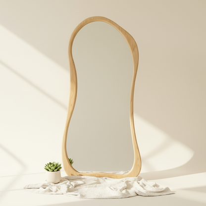 Wooden-framed mirror on a light surface with a plant and white fabric