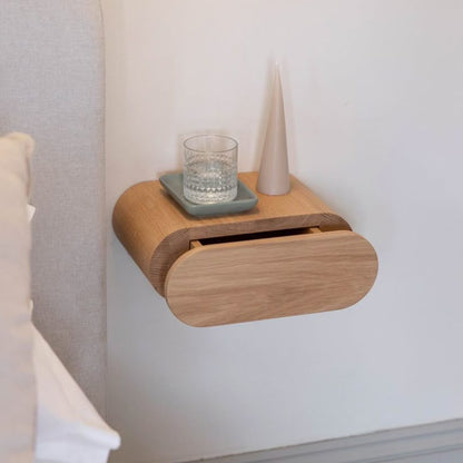 A Good Life minimalist floating bedside table in light wood with a glass of water and a decorative vase