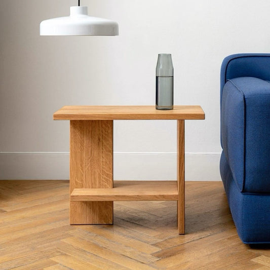 A Good Life minimalist quiet nightstand in natural wood next to a blue sofa and modern white hanging lamp