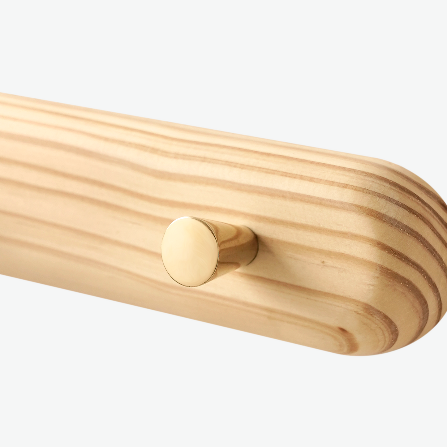 A Good Life minimalist wall hanger made of light wood with a smooth brass peg for hanging items