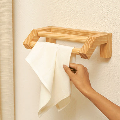 A Good Life minimalist wooden hand towel rail mounted on a wall holding a white towel with a hand reaching for it