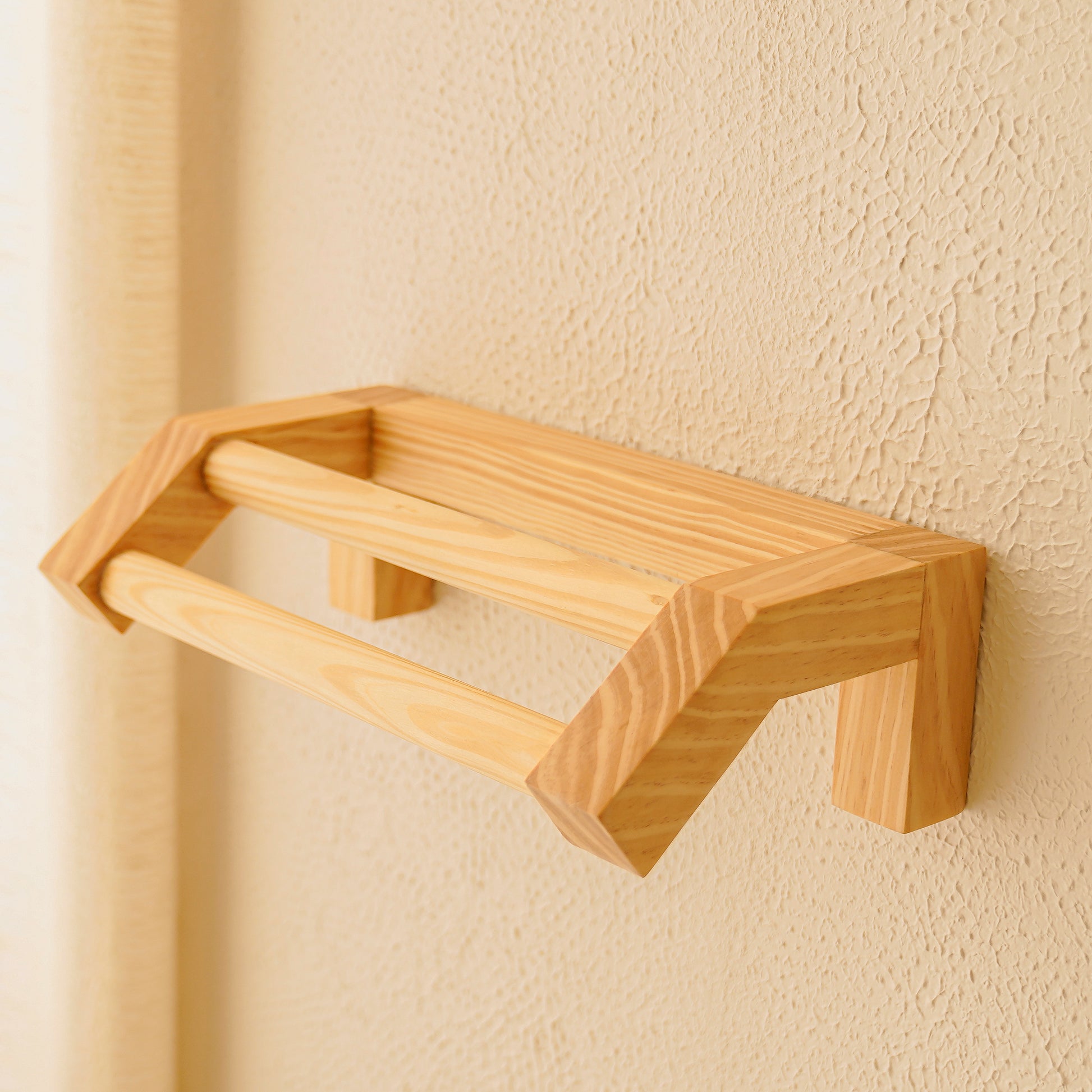 Minimalist wooden hand towel rail mounted on textured beige wall by A Good Life