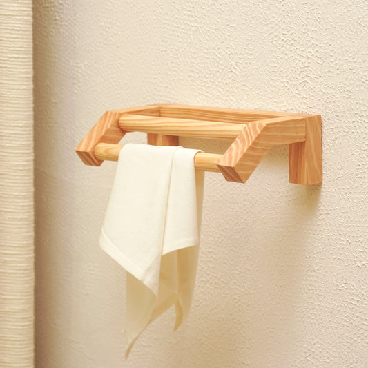 Minimalist wooden hand towel rail mounted on wall with a white towel hanging from it