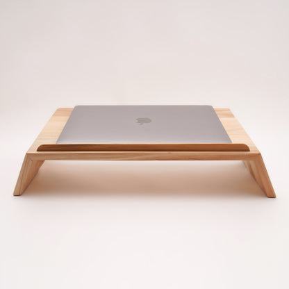 A Good Life pinewood ergonomic work desk laptop stand with a sleek wooden design holding a closed silver laptop
