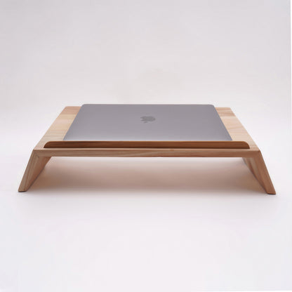 A Good Life pinewood ergonomic work desk laptop stand with a sleek wooden design holding a closed silver laptop