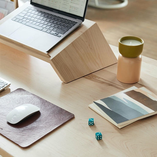 A Good Life pinewood ergonomic work desk laptop stand holding a laptop on a wooden desk with mouse and decor